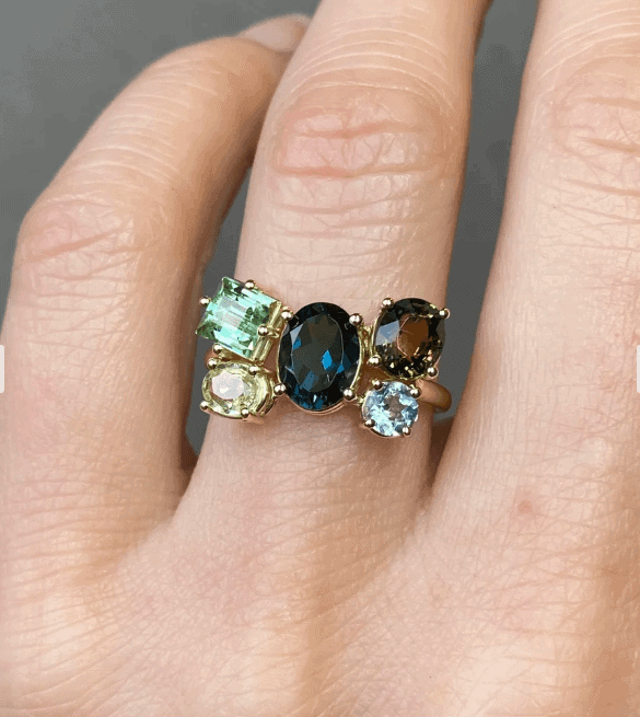Hand met een ring van Manon Herrewijnen met vijf gekleurde edelstenen